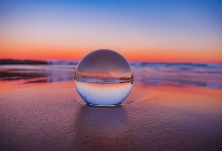 Crystal Ball - clear glass ball on gray sand during sunset