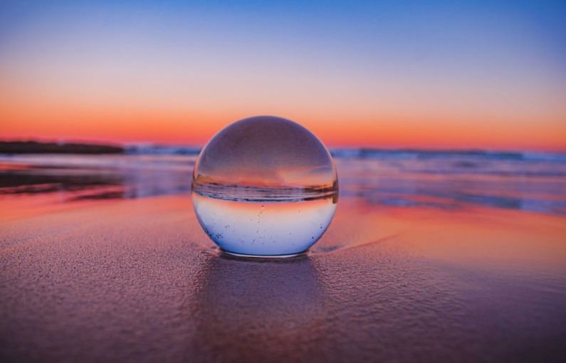 Crystal Ball - clear glass ball on gray sand during sunset