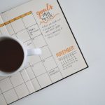 Content Calendar - white ceramic mug with coffee on top of a planner