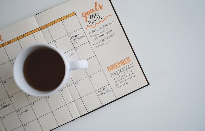 Content Calendar - white ceramic mug with coffee on top of a planner
