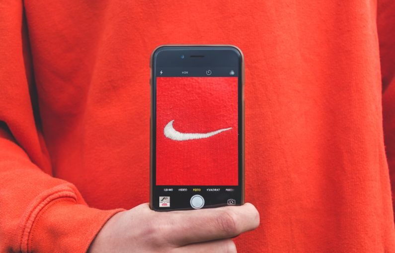 Brand Loyalty - person holding iPhone taking picture on Nike label